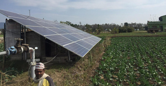 Auf einem Feld steht eine solarbetriebene Wasserpumpe für eine Dorfgemeinschaften
