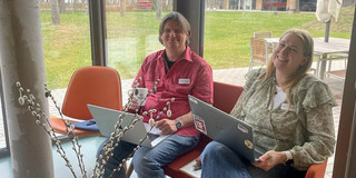 Tobias Haertel und Amrei sitzen mit Notebooks auf den Knien auf einem Sofa.