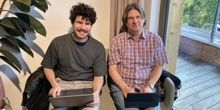 Tobias Haertel und Noah Daoud sitzen mit Notebooks auf den Knien auf einem Sofa.