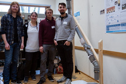Vier Studierende der Hochschule RuhrWest stehen neben einem Modell für ein Wasserleitungssystem, das sie aus Rohren und Leisten gebaut haben.