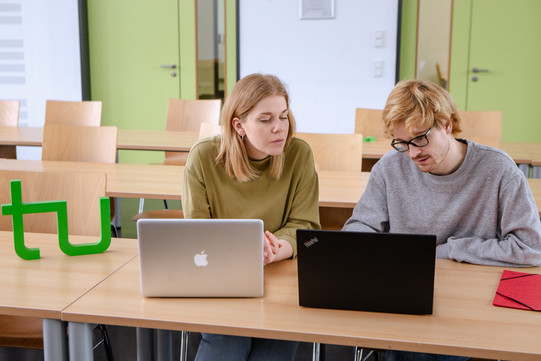 Studierende Laptops Zwei Studierende im Seminarraum sitzen vor ihren Laptops. Daneben das TU Logo.